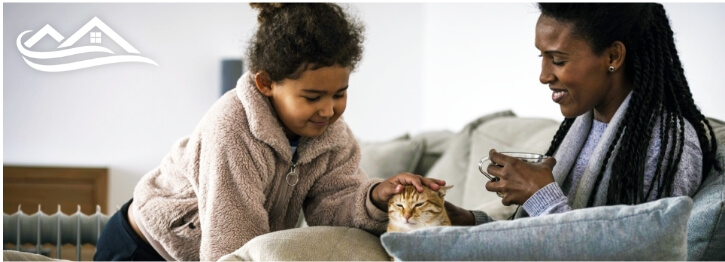 Woman and child sitting on a couch with a cat